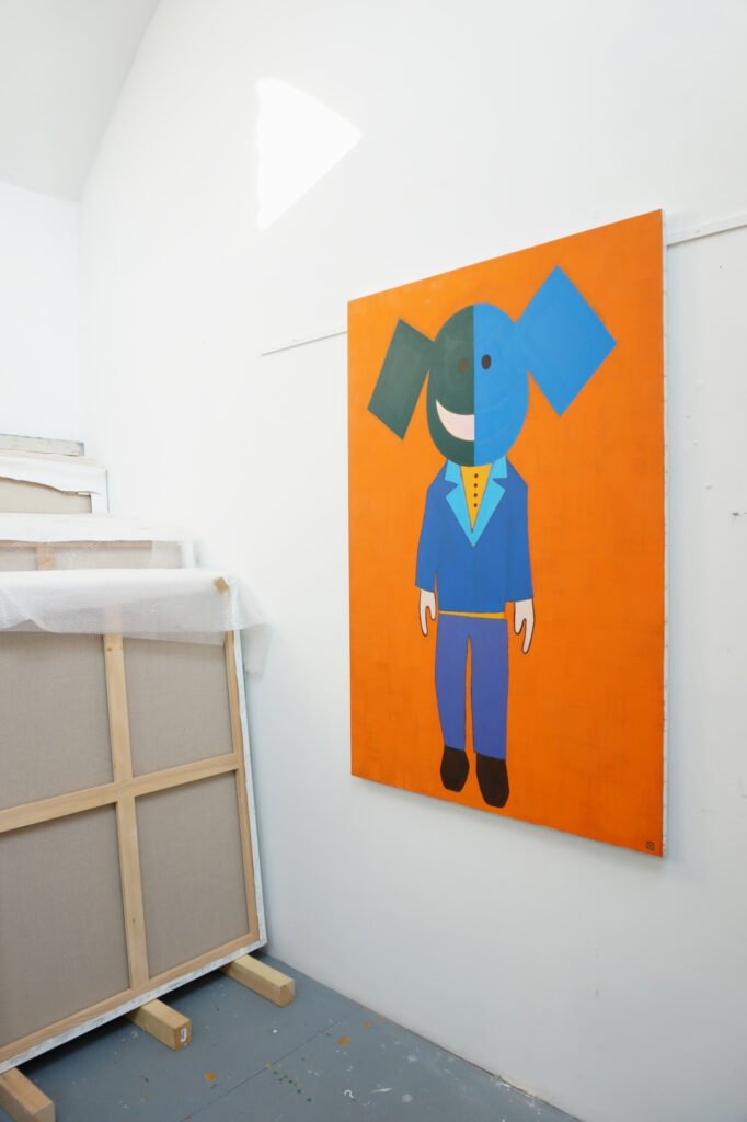 Ici on peut voir Une peinture de Benoît Andro qui représente un personnage géométrisé constitué de formes simples et colorées sur fond orange.