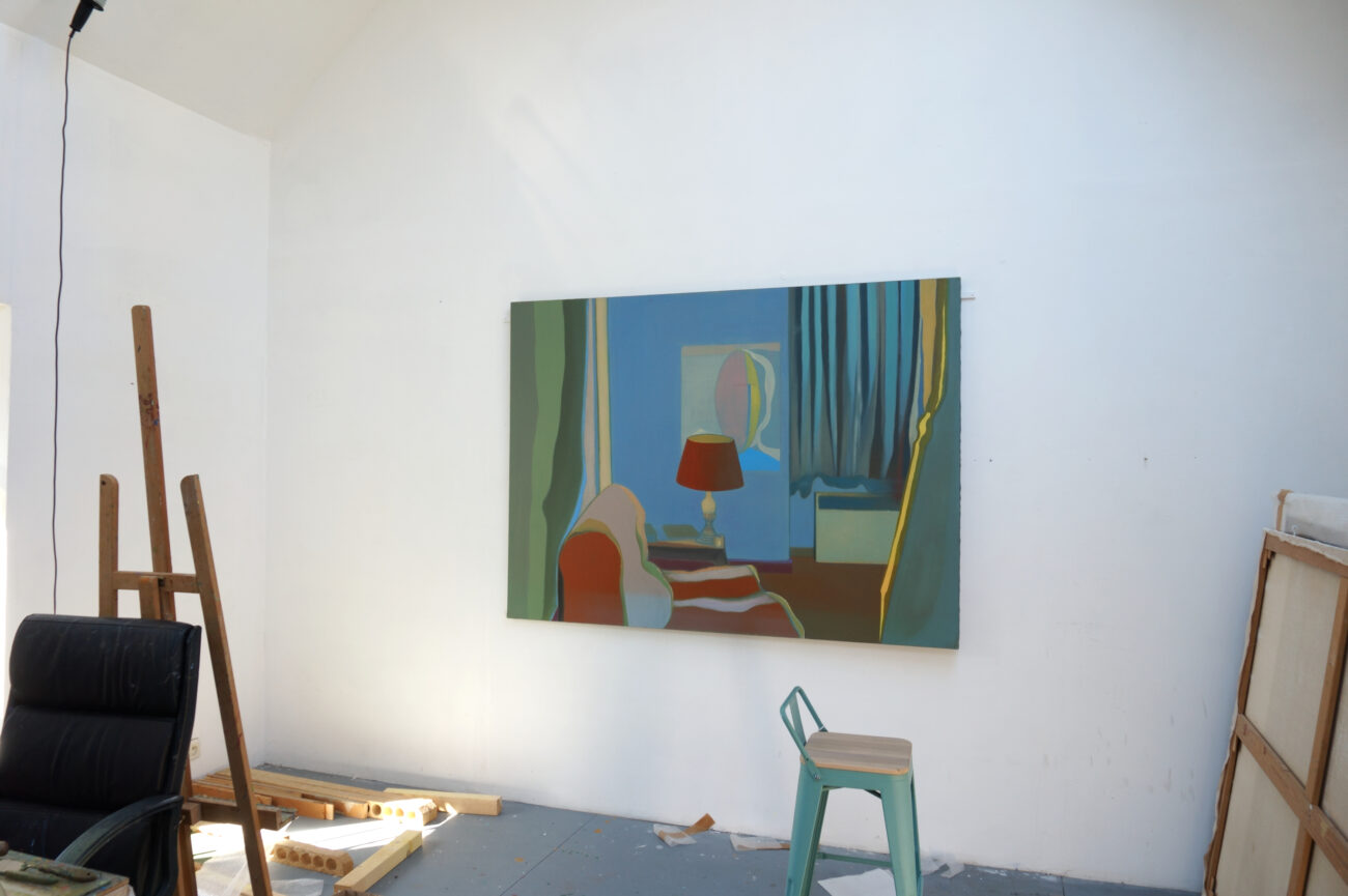 Ici on peut voir une peinture dans l'atelier de Benoît Andro qui représente un intérieur avec une lampe et un poster ainsi qu'un fauteuil. Le tout est traité en aplats.