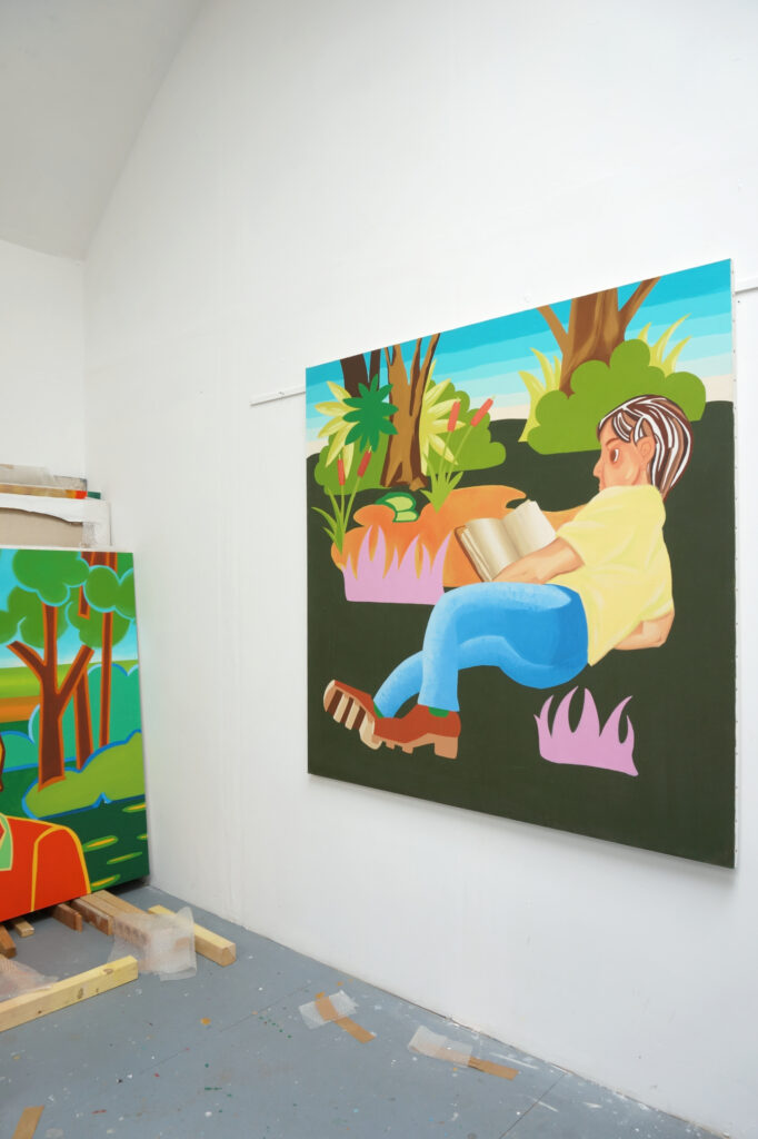 Peinture accrochée au mur dans l'atelier de l'artiste peintre Benoît Andro qui représente un personnage en train de lire un livre en plein-air